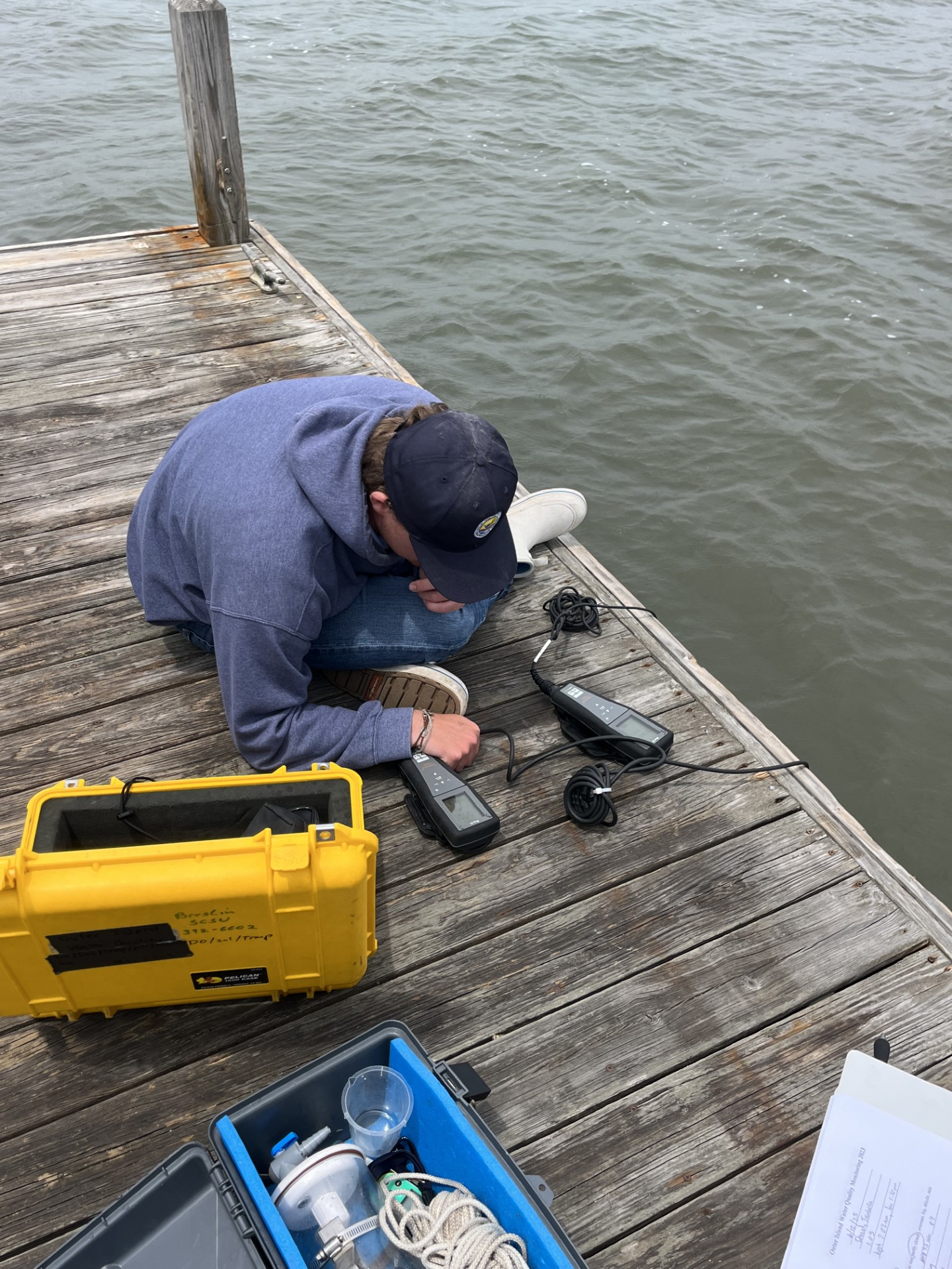 Man sitting on pier reading measurement device